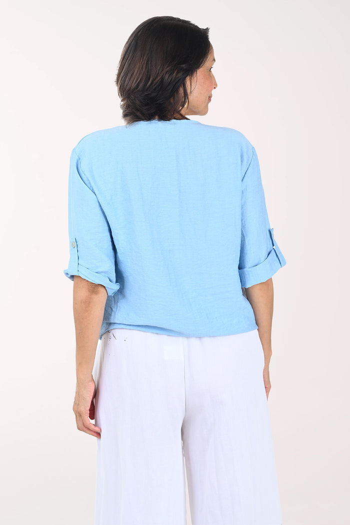 Woman wearing a light blue top and white pants on a white background