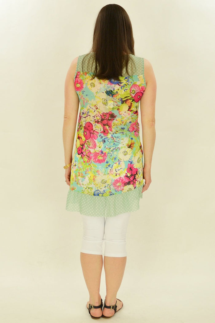 Pink Meadow Flowers Tunic by Whispers featuring a flowy fabric with pink and green floral patterns, displayed on a hanger.
