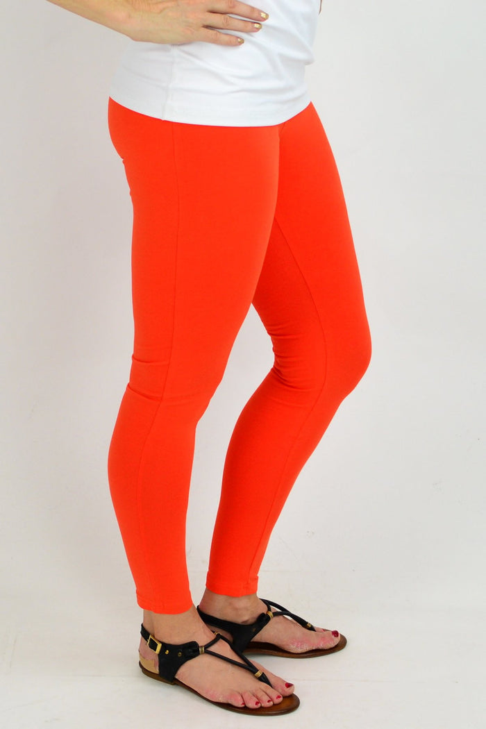 Orange ankle length leggings by David Jessie, close-up of fitted fabric and vibrant color on a model.