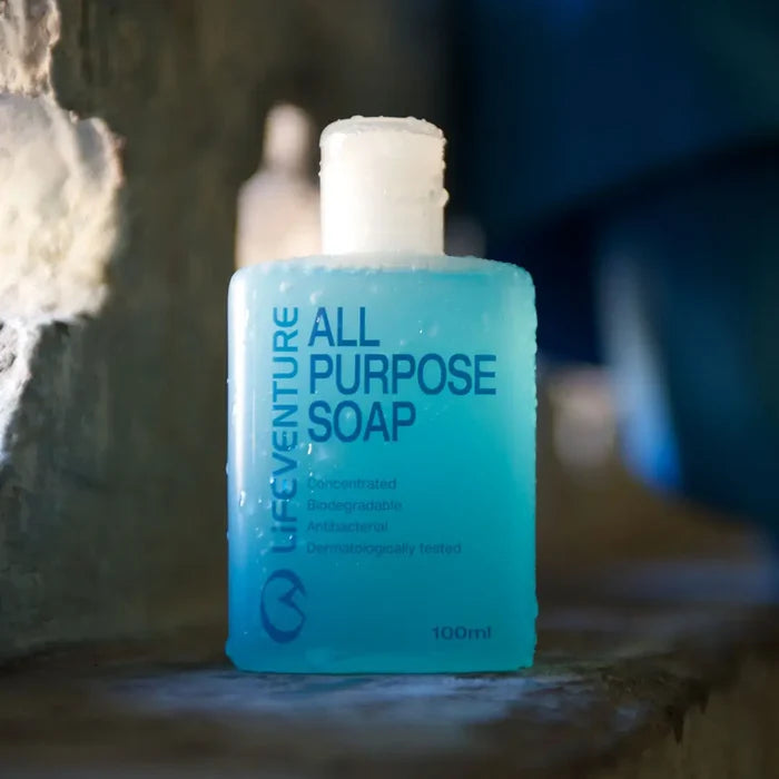 A 100ml bottle of Life Venture All Purpose Liquid Soap with a translucent light blue body and a white cap, standing on a rustic wooden surface against a blurred background.