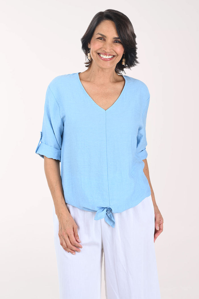 Woman wearing a light blue top and white pants on a white background