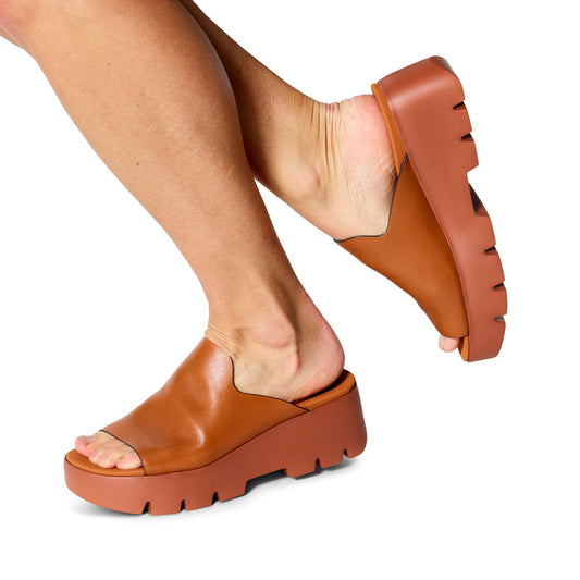 Brown platform sandals worn by a person on a white background