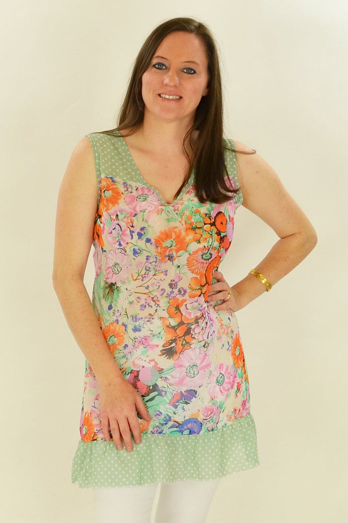 Whispers Orange Meadow Flowers tunic displayed on a hanger with vibrant floral pattern and lightweight fabric.