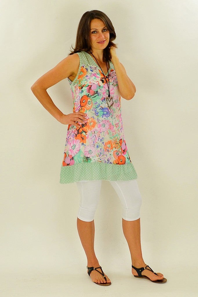 Whispers orange meadow flowers tunic displayed on a hanger, featuring vibrant floral pattern and lightweight fabric.