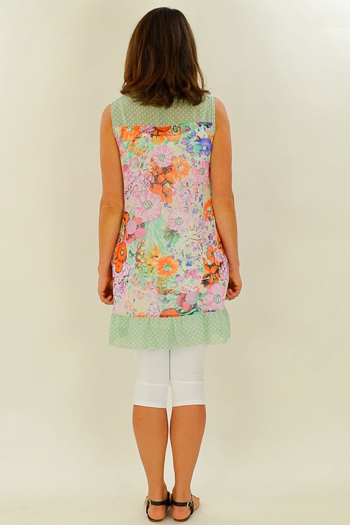 Whispers orange Meadow Flowers tunic with vibrant floral pattern, lightweight fabric, and relaxed fit, displayed on a hanger.