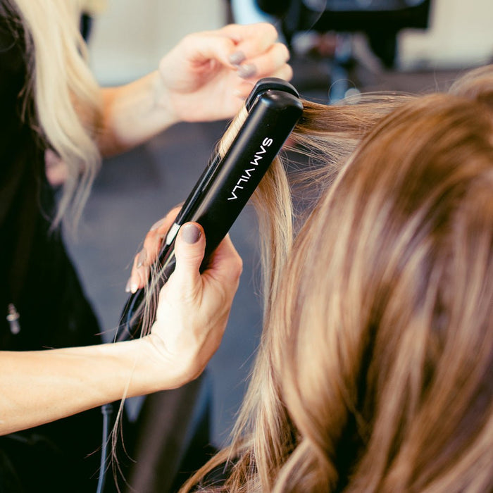 Stylist creating smooth, straight hair with the Sam Villa SLEEKR Professional Flat Iron.